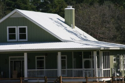 Galvalume rib roofing over a green, paneled house